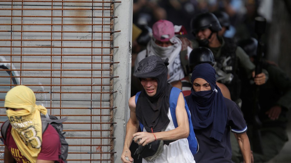 Demonstrators run away from security forces at a rally in Caracas on July 27, 2017. 