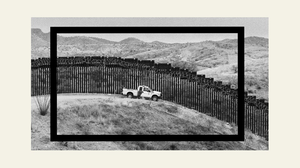 a truck parked in front of the border wall between the U.S. and Mexico