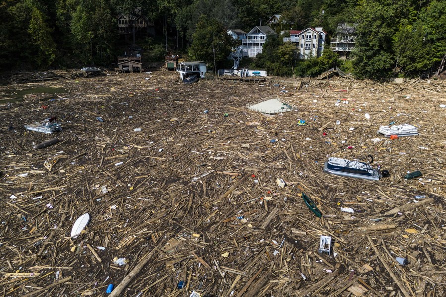 The surface of a lake is completely covered by floating debris and stranded boats.