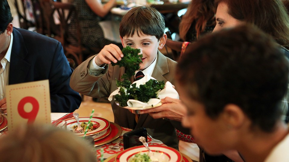 A young boy holds a leaf of kale during a meal at the White House.