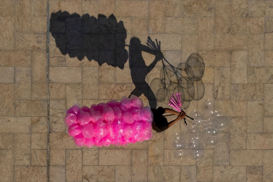 An aerial view shows a vendor selling cotton candy and balloons.