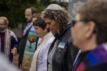 A row of Jews, one wearing a kippah, pray as they mourn the Boulder attack