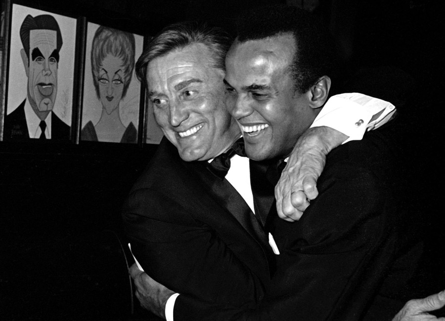 Kirk Douglas and Harry Belafonte embrace each other playfully.