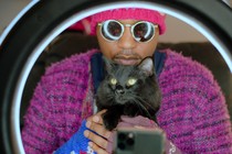 A cat person holding his black cat in front of a ring light