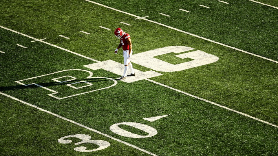 A football player walking across a football field.