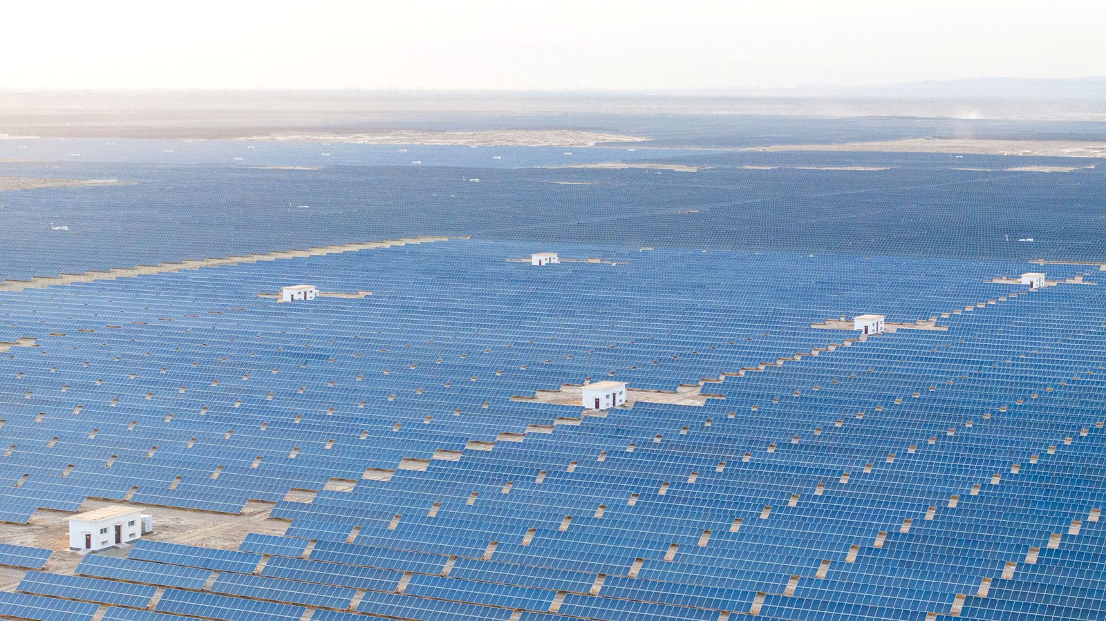An aerial view—solar panel grids in a desert, stretching to the horizon