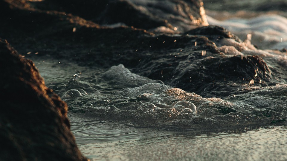 A photo of water swirling around basaltic rocks