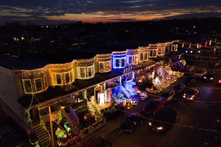 Rowhouses are seen covered in holiday decorations at night.