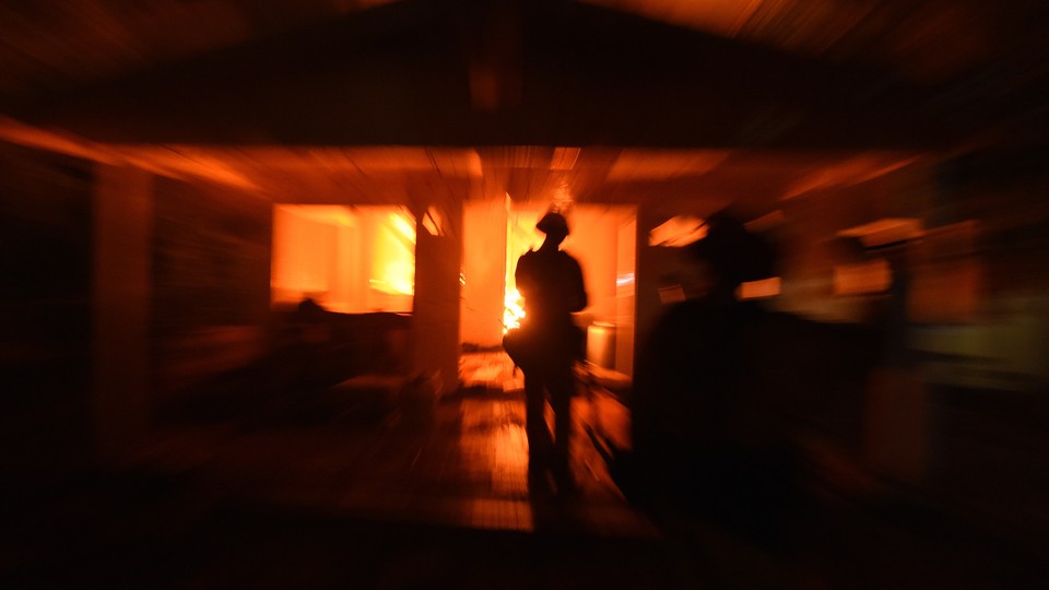 A firefighter surveys a burning house.