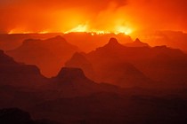 A night view of a smoky Grand Canyon, with a wildfire burning along the far rim.