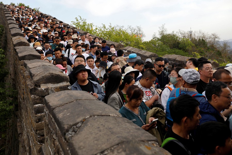 A large crowd of people fills the pathway atop a section of the Great Wall of China.
