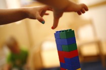 Two children's hands grab for a tower of LEGOs. 