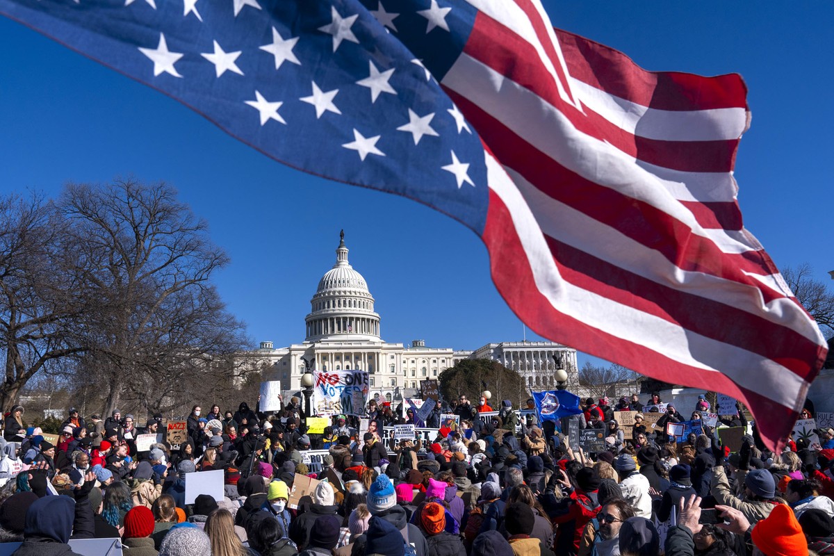 An American flag flies upside-down above a group of protesters gathered near the U.S. Capitol Building.