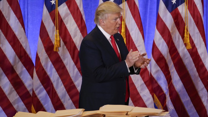 President-elect Donald Trump stands by a table covered with paperwork