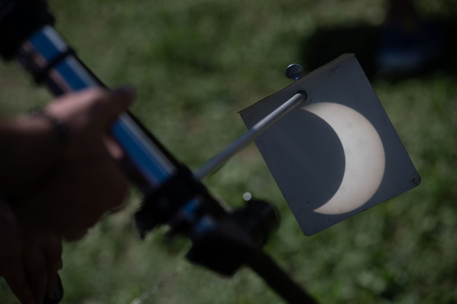 A partial eclipse is visible on a card placed in front of a telescope's eyepiece.