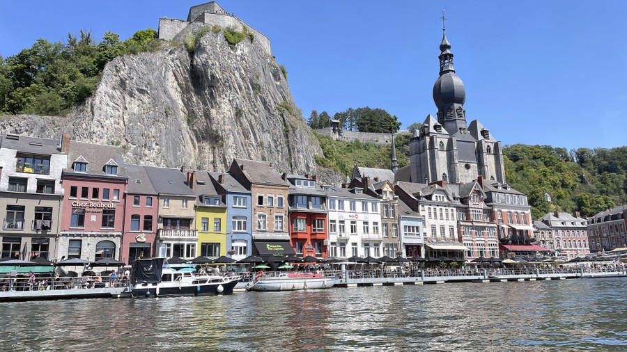 Historical buildings stand along a riverbank in Belgium.