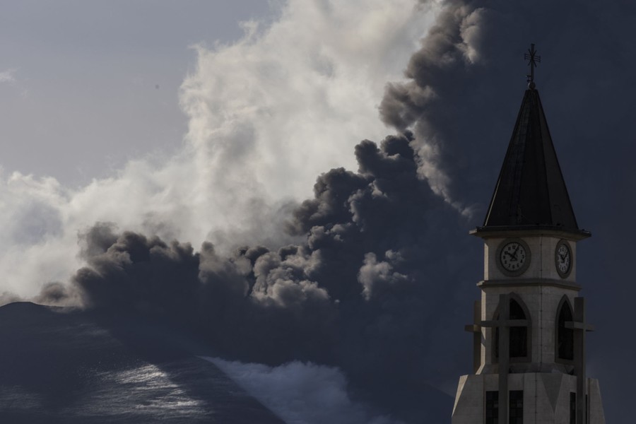 A plume ash and steam rises behind a church steeple.