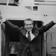 A black and white photograph of Richard Nixon raising his arms in celebration.