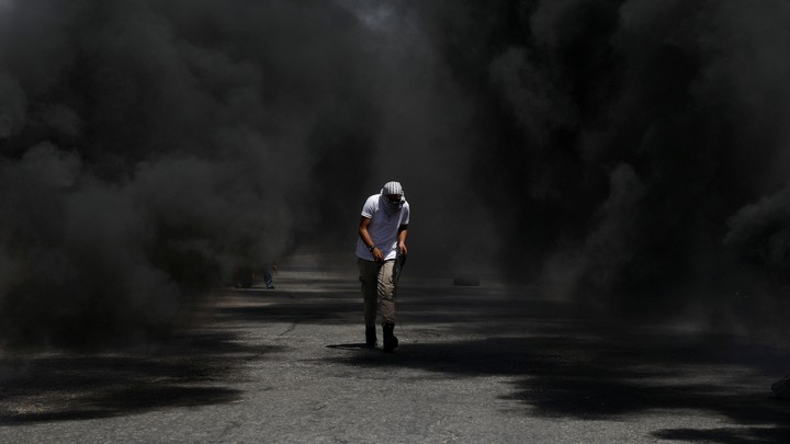 A protester crouching in black smoke