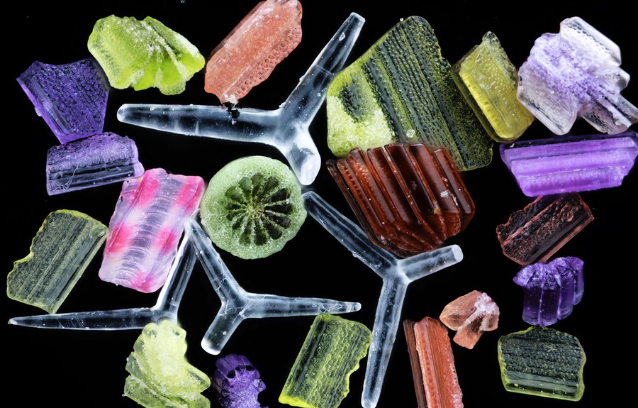 A microscopic view of varied pieces of beach sand, shaped like chunks, shards, and spikes