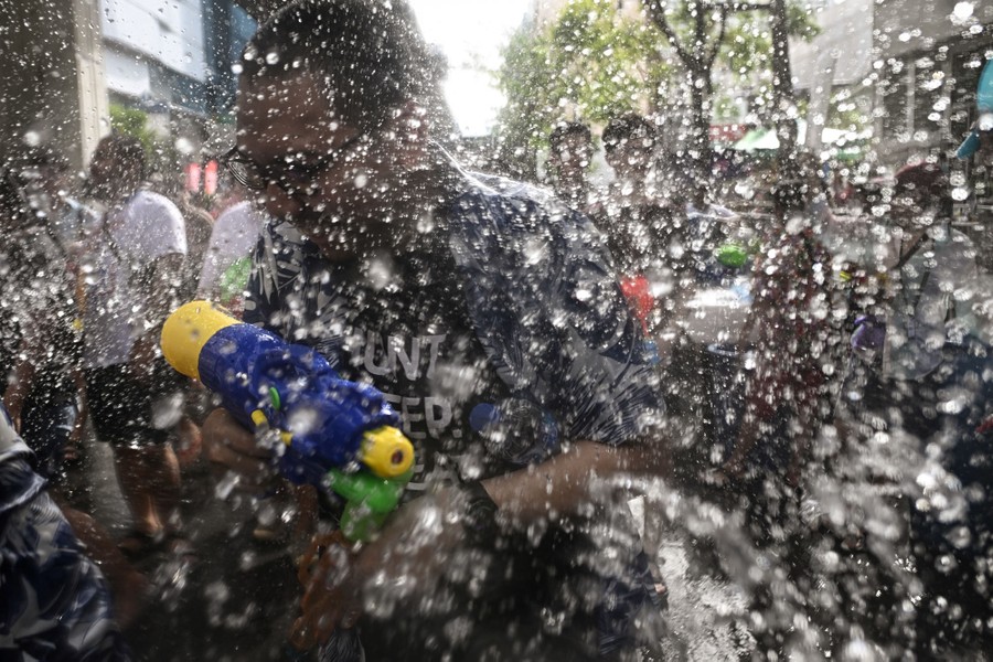 People duck and play in a street, surrounded by splashing water.