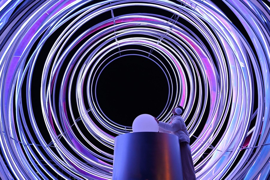 A person looks up at a series of large, concentric illuminated circles.