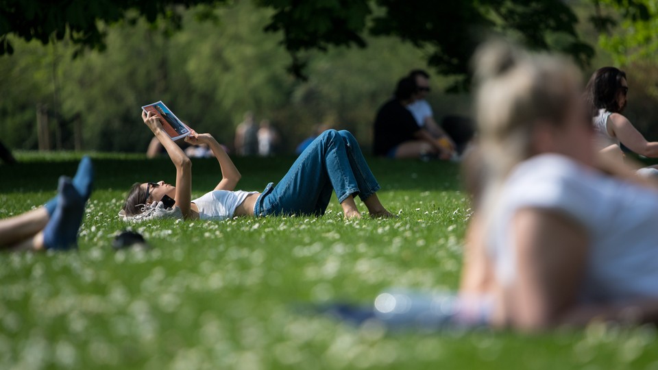 A person laying in the grass and reading