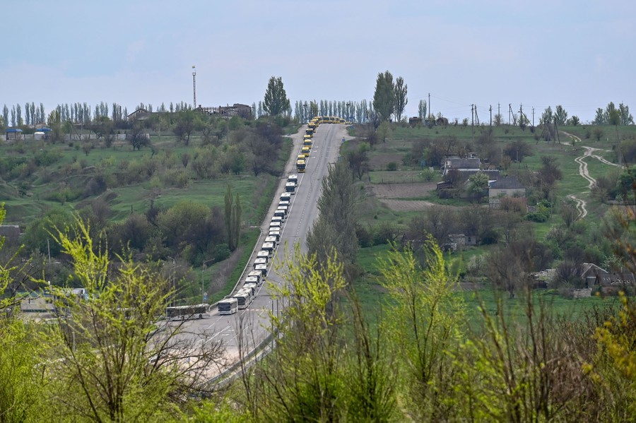 A long line of buses on a road on a hillside