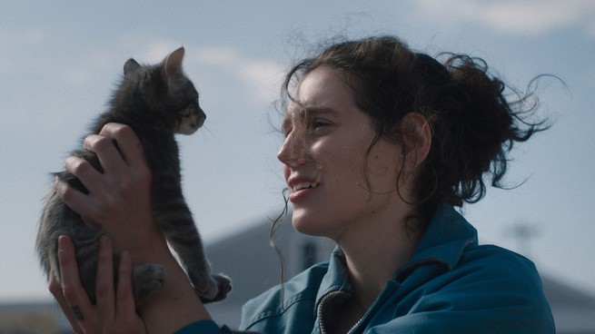 A young woman holds a kitten looking at it
