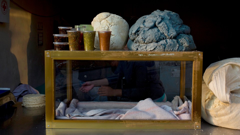 an empty case on a table with tortillas next to it and plastic containers with sauces on top