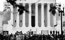 A black-and-white photo of protesters outside the entrance of the Supreme Court Building