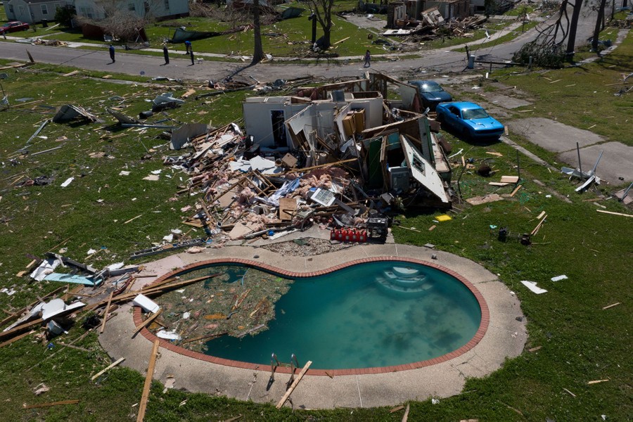 An aerial view of a storm-damaged neighborhood, yards strewn with debris.