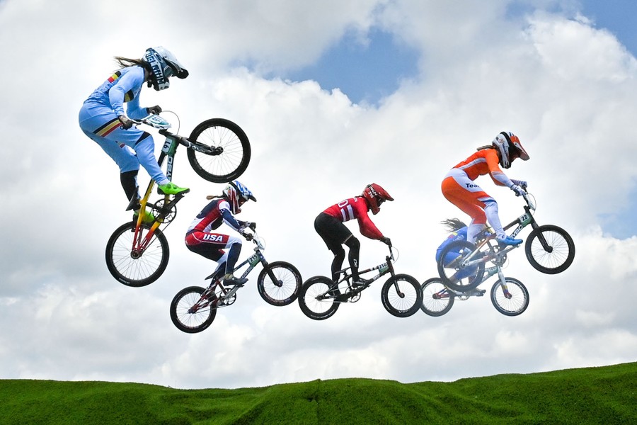 Five BMX racers jump through the air together.