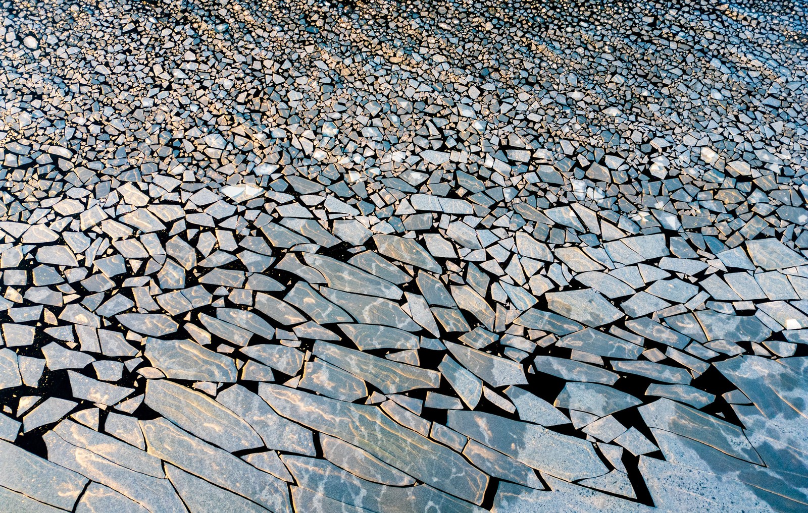 Hundreds of broken-up sheets of ice float on a body of water.