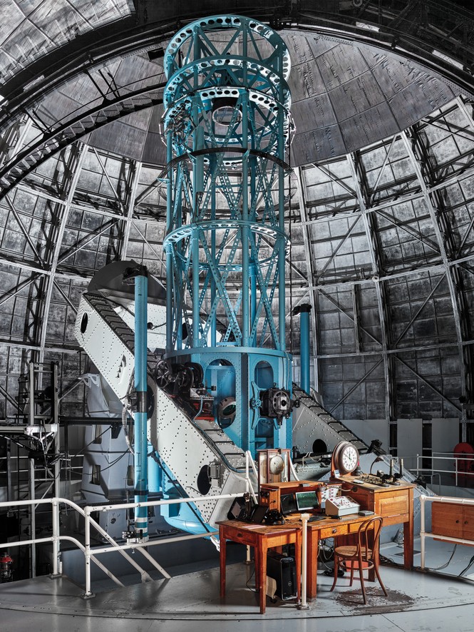 photo of towering blue scaffolding inside a large domed roof, with antique wooden desk at base holding original instruments along with modern additions