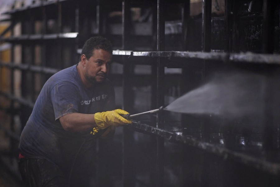 A man hoses down a supermarket shelf.