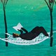 A woman reads a book while resting on a hammock between trees