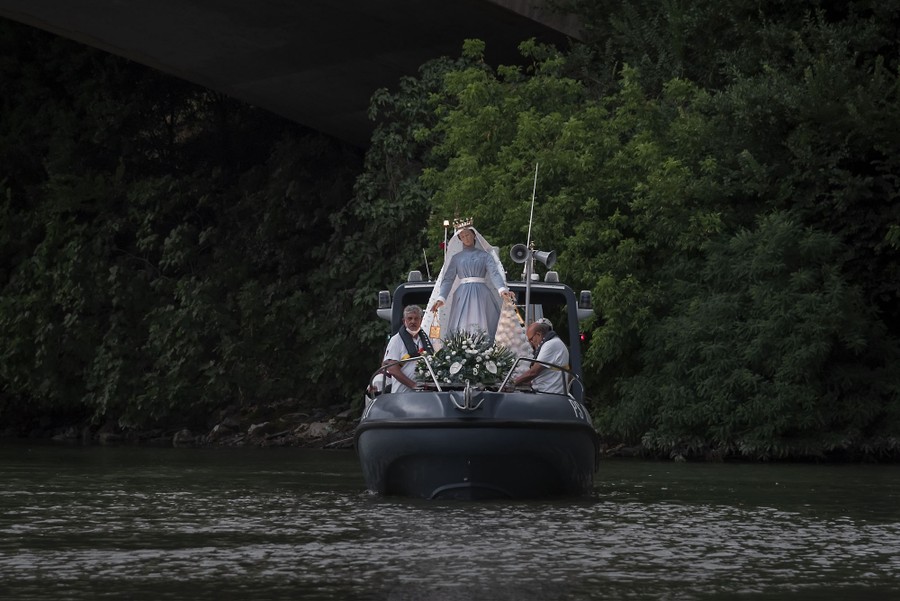 A statue of the Virgin Mary is transported aboard a small boat.