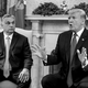 black-and-white photo of Viktor Orbán looking at Donald Trump speaking, both dressed in dark suits and ties, sitting in armchairs in front of fireplace