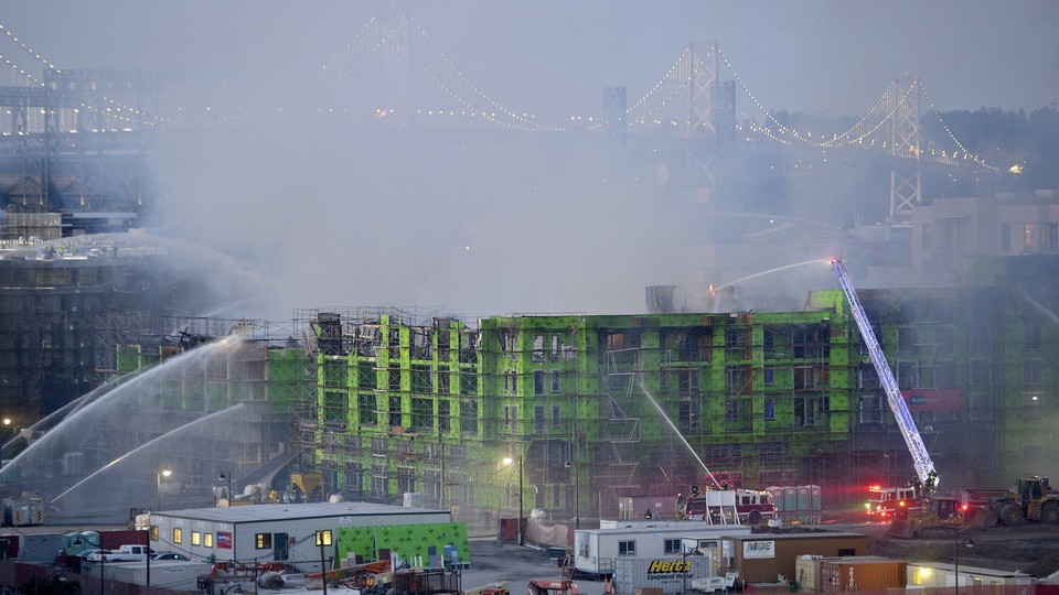Firefighters spray water on a burning, partially completed apartment building in the San Francisco Bay Area.