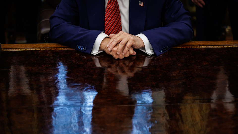 Photograph of Donald Trump from the neck down with his hands on his desk