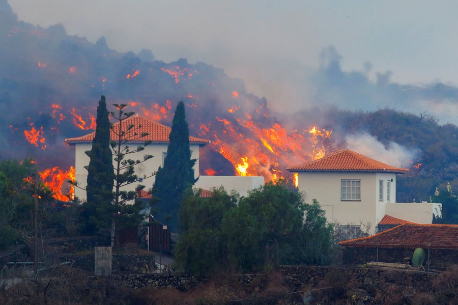 A huge lava flow approaches a house.