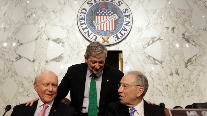 Senator John Kennedy (standing) speaks with Senators Orrin Hatch (left) and Chuck Grassley.