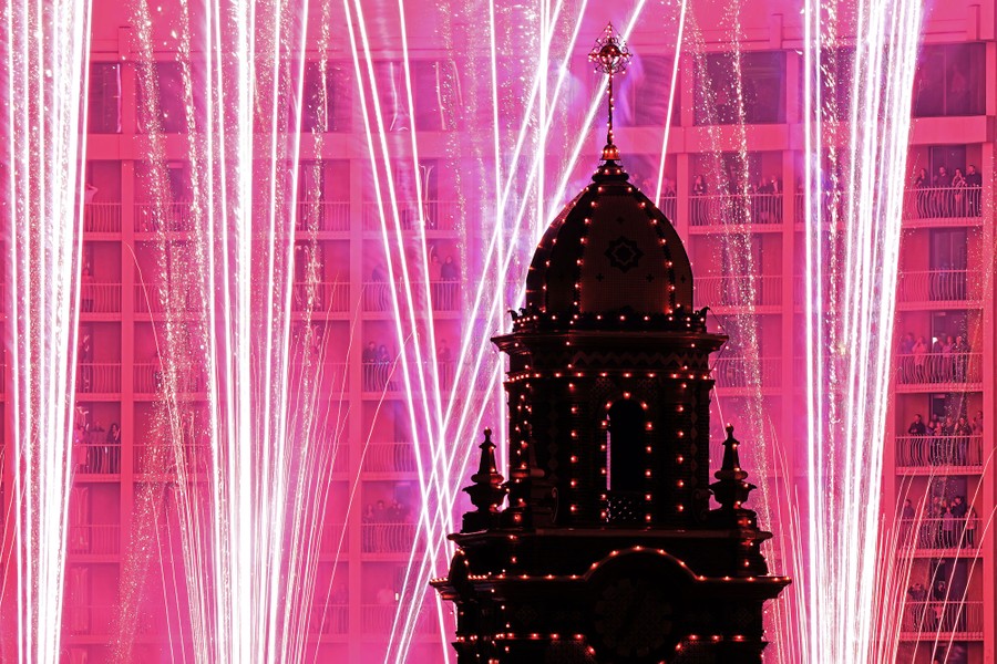 Fireworks light up the sky behind an illuminated spire.