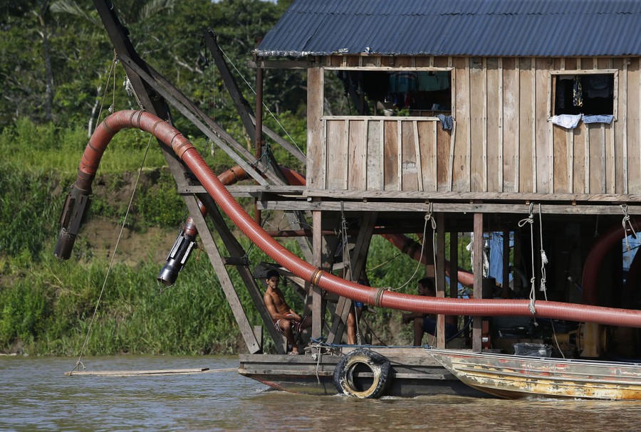 People sit on a barge that is outfitted with a large hose.