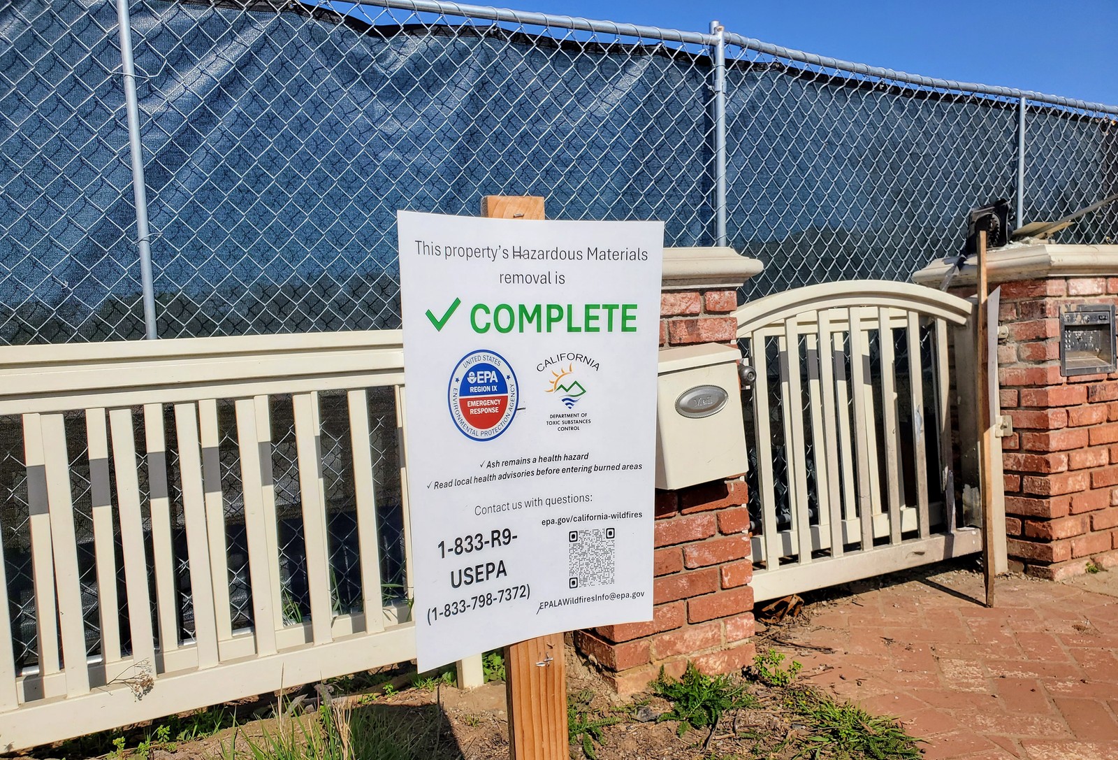 The sign stands outside, a fenced off residential lot, reading