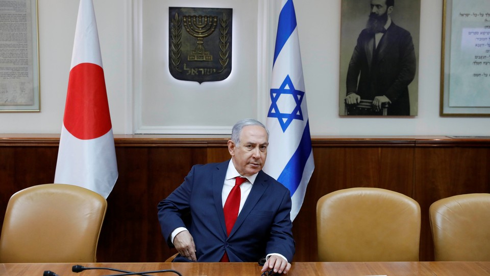 Benjamin Netanyahu sits in his office in front of a portrait of the Zionist leader Theodor Herzl.