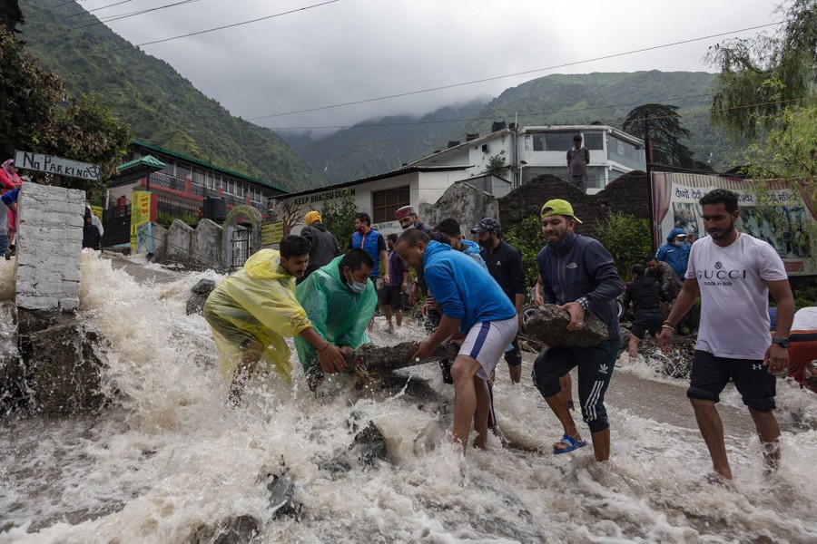 Several people place rocks in rushing floodwater.