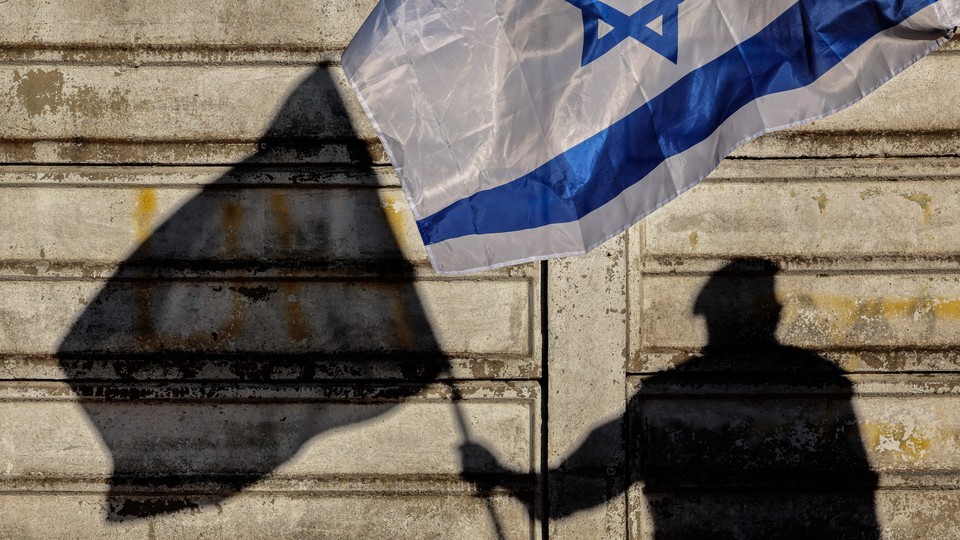 A photo of a silhouette of a man holding an Israeli flag