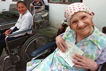 An elderly woman holds her birth certificate at a retirement home.